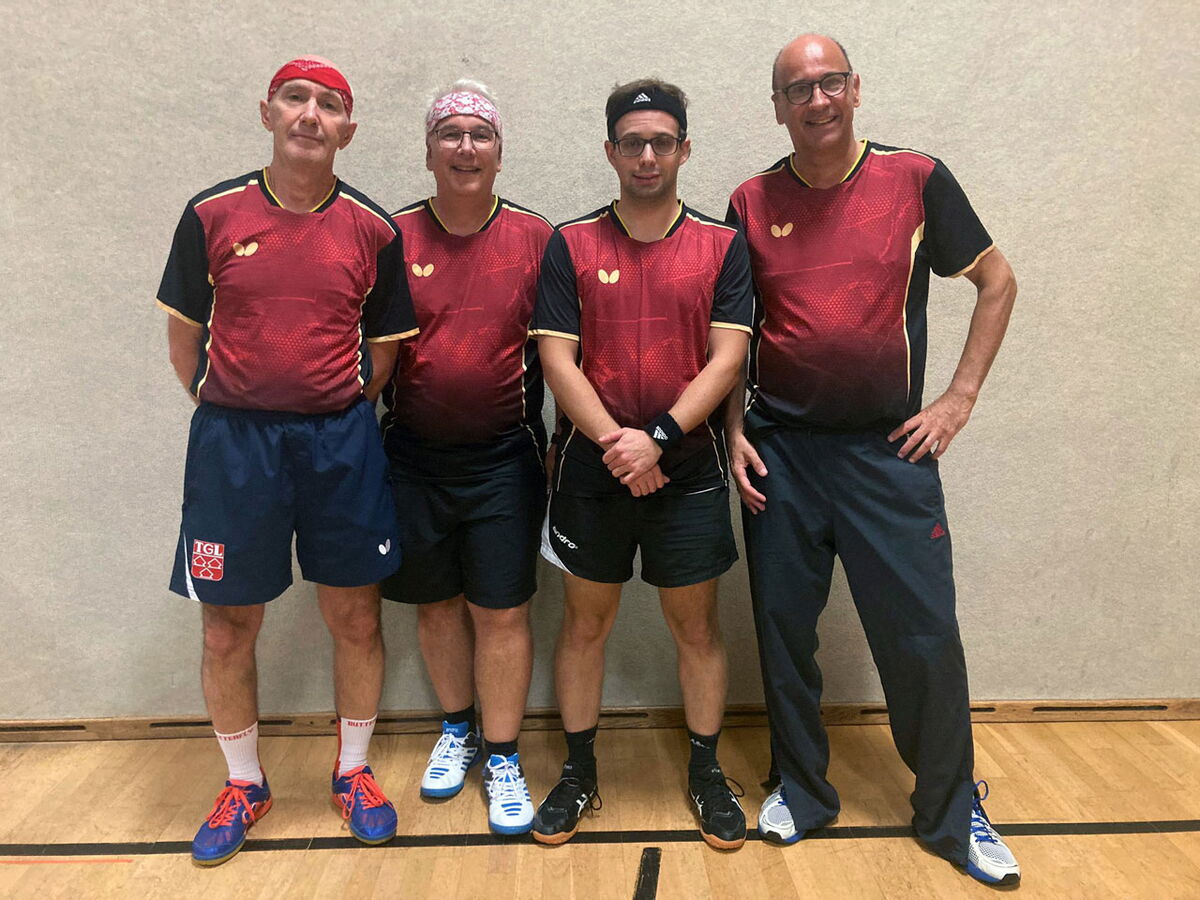 Vier Männer in einheitlichen Sporttrikots posieren lächelnd in einer Turnhalle des Turnvereins Landshut.