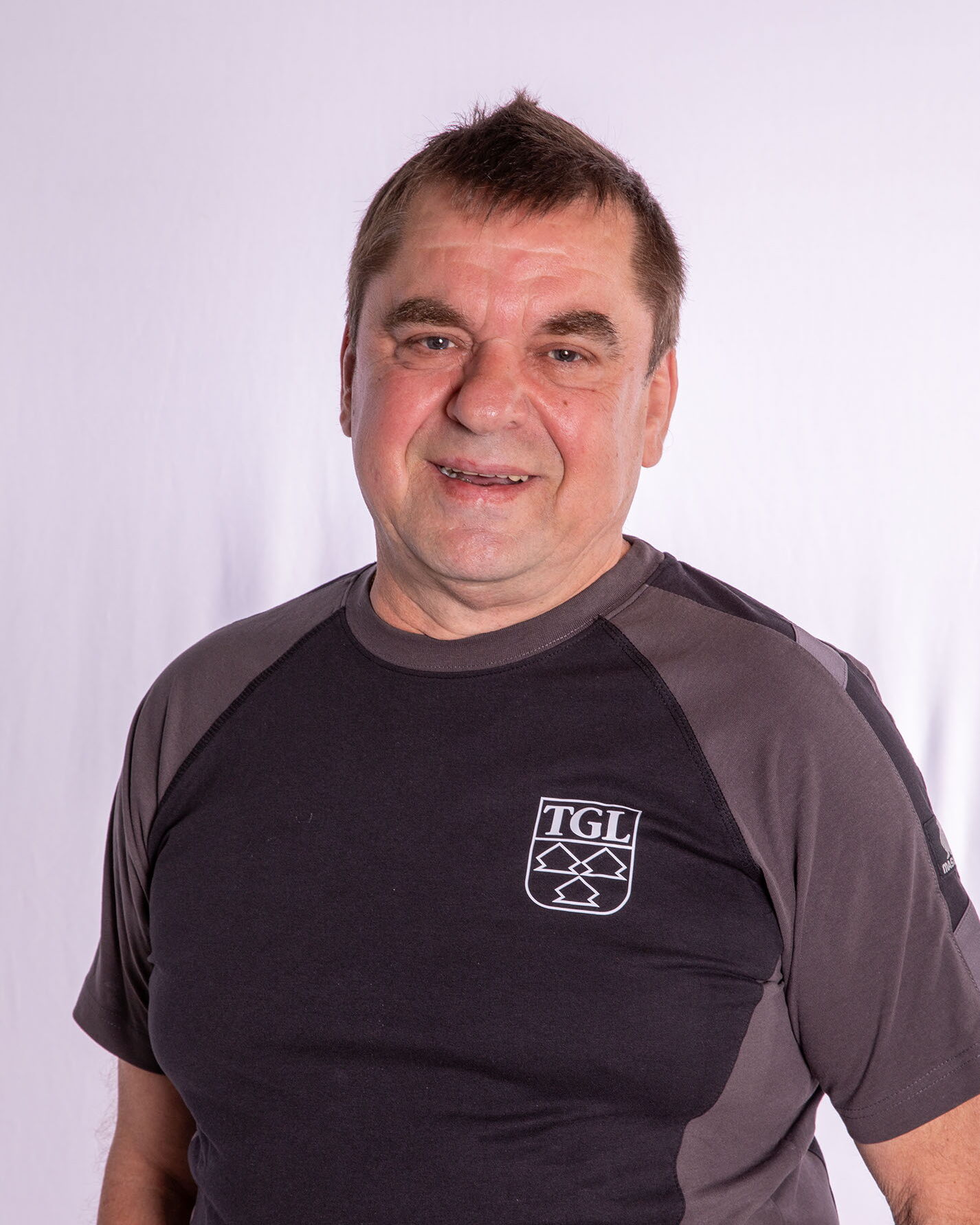 Ein lächelnder Mann im TGL-Shirt repräsentiert stolz den Sportverein Turngemeinde Landshut.