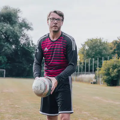 Ein Mann hält einen Ball auf einem Sportplatz der Turngemeinde Landshut, bereit für das nächste Spiel.