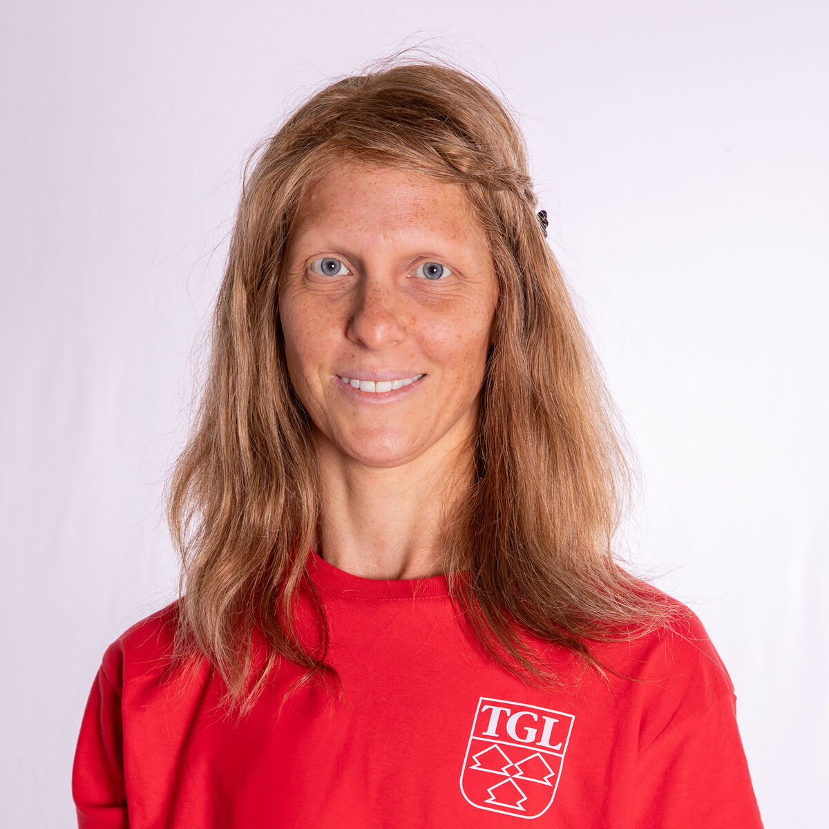 Eine junge Frau im roten TGL-Shirt lächelt freundlich in die Kamera, repräsentativ für den Verein in Landshut.
