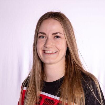 Eine Frau in rotem Sporttrikot lächelt, repräsentierend den Verein Turngemeinde Landshut.