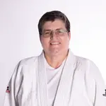 Eine Frau in einem weißen Judoanzug lächelt freundlich in die Kamera, repräsentiert den Sportverein Landshut.