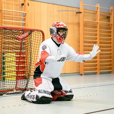 Ein Floorball-Torwart der Turngemeinde Landshut verteidigt konzentriert das Tor in einer Sporthalle.