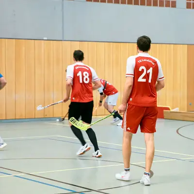 Spieler der TG Landshut in roten Trikots spielen Floorball in einer Sporthalle des Vereins.