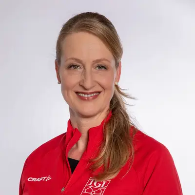 Eine lächelnde Frau im roten TGL-Shirt präsentiert stolz ihre Zugehörigkeit zum Sportverein.