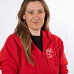 Eine Frau in einem roten TGL-Shirt lächelt in die Kamera, repräsentiert den Sportverein Turngemeinde Landshut.