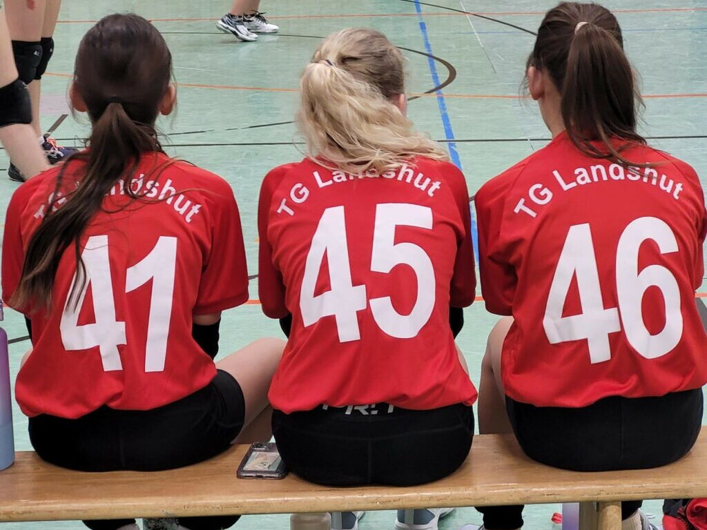 3 Mädchen mit TGL Triko, auf einer Bank in der Sporthalle 