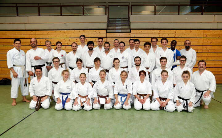 Eine Gruppe von C-Trainern posiert in Karateanzügen in einer Turnhalle, Teil des Vereins Turngemeinde Landshut.