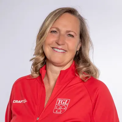 Eine lächelnde Frau im roten TGL-Shirt präsentiert stolz ihre Zugehörigkeit zum Sportverein.