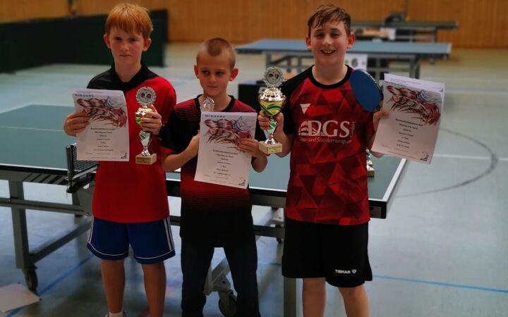 Drei Jungen präsentieren stolz ihre Pokale und Urkunden bei einem Tischtennisturnier der Turngemeinde Landshut.