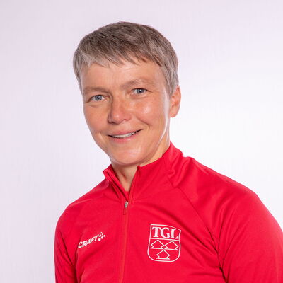 Eine Frau in roter TGL-Jacke lächelt freundlich in die Kamera, symbolisierend die Fitness bei der Turngemeinde.