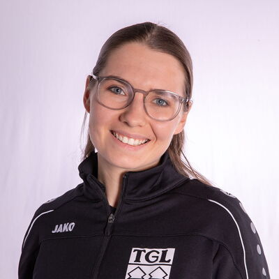 Eine Frau im TGL-Jackett lächelt in die Kamera, stolz auf ihre Zugehörigkeit zur Turngemeinde Landshut.