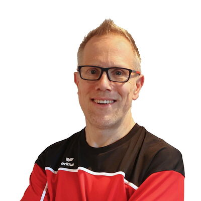 Ein Mann in Sportkleidung lächelt mit verschränkten Armen, repräsentierend den Verein Turngemeinde Landshut.