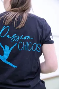 Eine Frau trägt ein schwarzes T-Shirt mit blauem "Chicas"-Schriftzug, das ihren Teamgeist im Sportverein Landshut zeigt.