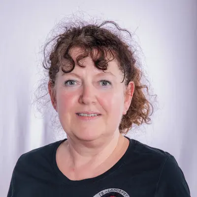 Eine Frau in einem schwarzen T-Shirt mit dem Logo der Turngemeinde Landshut lächelt in die Kamera.