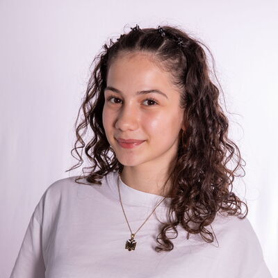 Eine junge Frau mit lockigem Haar lächelt freundlich in die Kamera, repräsentiert den Sportverein Landshut.