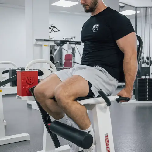 Ein Mann trainiert konzentriert auf einem Fitnessgerät, während er ein TGL-Shirt im Turngemeinde Landshut Verein trägt.