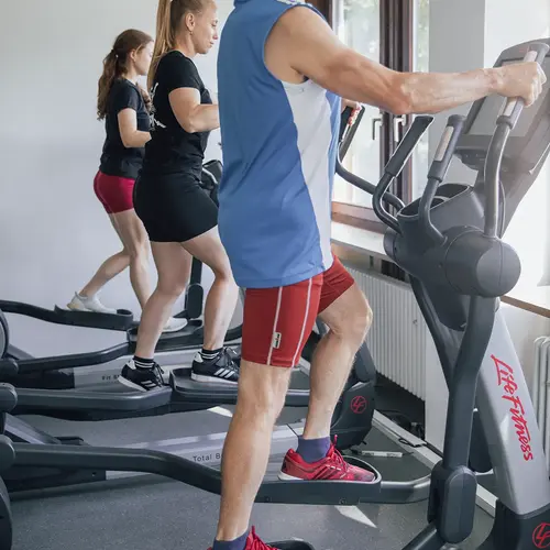Mehrere Personen trainieren im Fitnessstudio der Turngemeinde Landshut auf Crosstrainern.