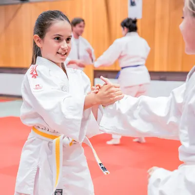 Ein Mädchen trainiert engagiert Judo im Sportverein Landshut auf der roten Matte.