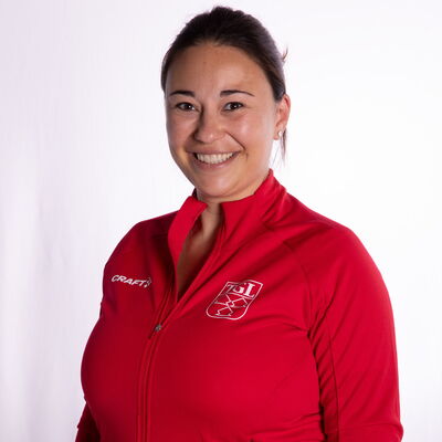 Eine Frau in einem roten TGL-Trikot lächelt freundlich in die Kamera und repräsentiert den Sportverein Landshut.