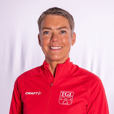 Eine lächelnde Frau trägt eine rote TGL-Jacke, symbolisierend den Sportgeist des Vereins Turngemeinde Landshut.