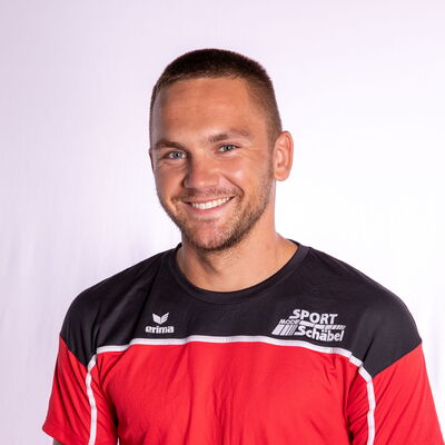Ein lächelnder Athlet im roten Trikot repräsentiert stolz den Sportverein Turngemeinde Landshut.