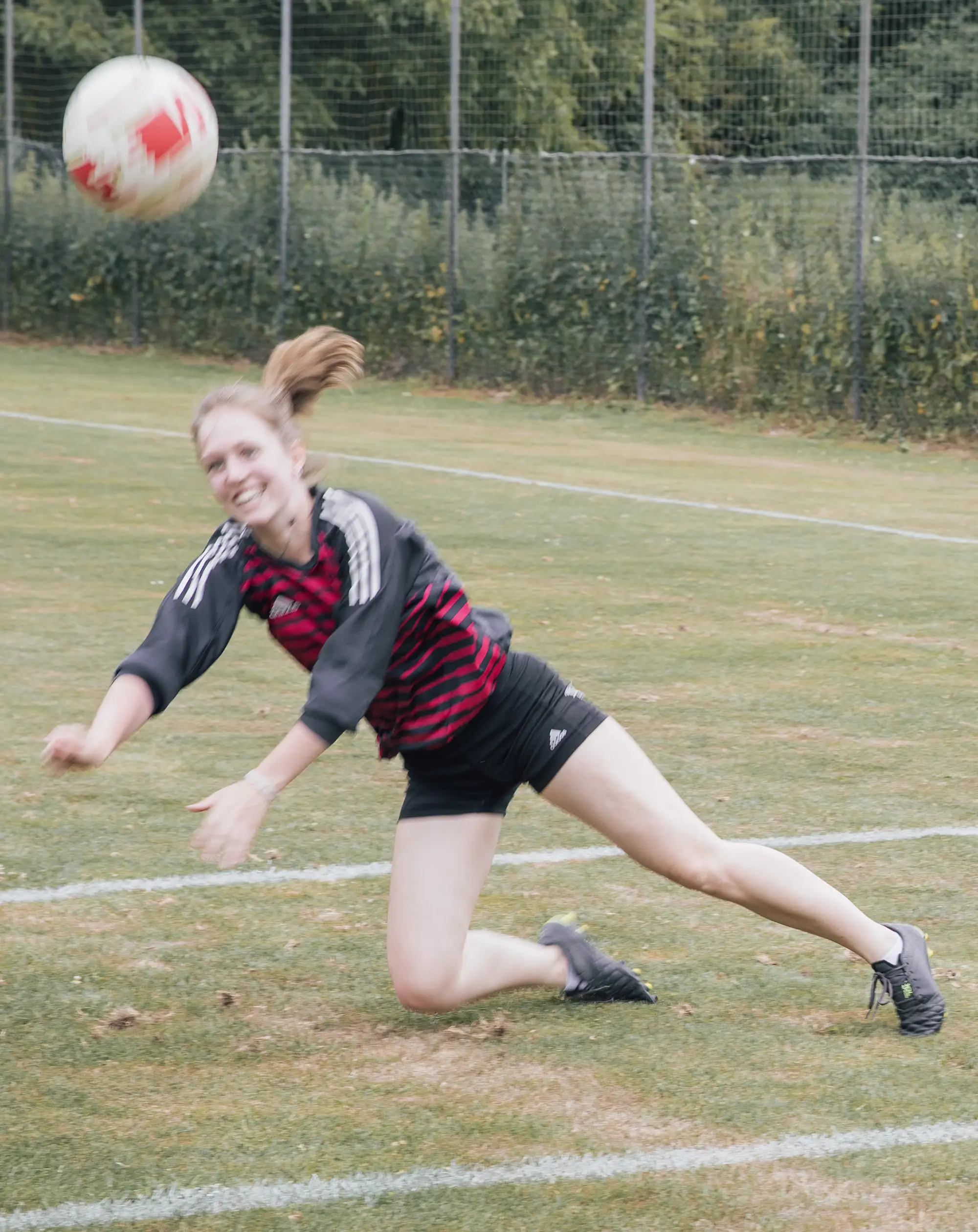 Eine Sportlerin der Turngemeinde Landshut hechtet auf einem Rasenplatz nach einem Ball.