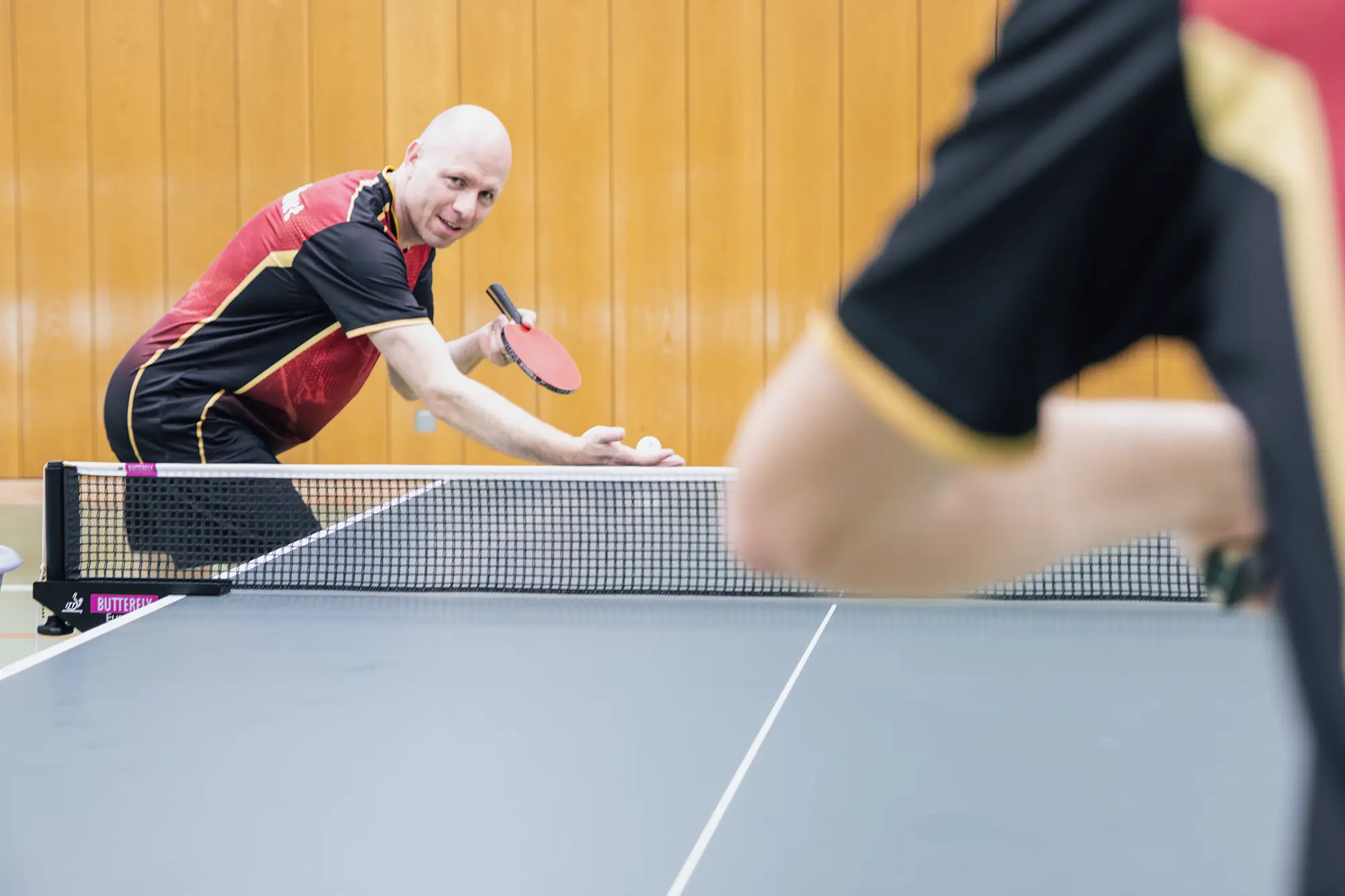 Ein Tischtennisspieler der Turngemeinde Landshut bereitet sich auf den Aufschlag in einem spannenden Match vor.